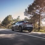 Lexus RZ circulando por carretera de montaña con paisaje natural.