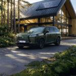Lexus TZ verde estacionado frente a una vivienda moderna rodeada de bosque.