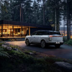 Lexus TZ blanco estacionado frente a una casa moderna en un bosque al anochecer.